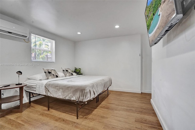 bedroom with a wall unit AC and light hardwood / wood-style floors