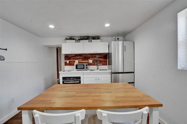 kitchen with appliances with stainless steel finishes, dark hardwood / wood-style flooring, tasteful backsplash, sink, and white cabinetry