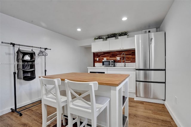 kitchen featuring a kitchen island, stainless steel appliances, white cabinetry, and light hardwood / wood-style floors