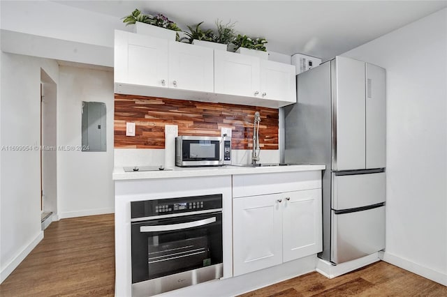 kitchen with white cabinetry, sink, electric panel, hardwood / wood-style floors, and appliances with stainless steel finishes