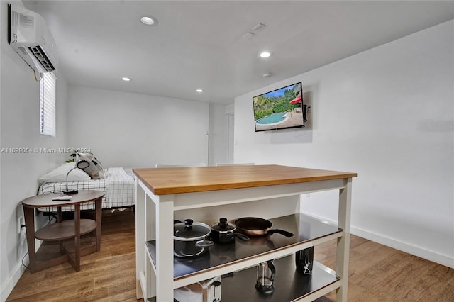 kitchen with an AC wall unit, butcher block counters, and light wood-type flooring