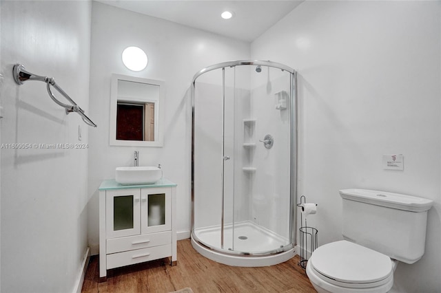 bathroom with hardwood / wood-style floors, vanity, an enclosed shower, and toilet