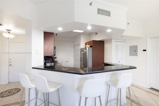 kitchen featuring kitchen peninsula, stainless steel fridge, crown molding, light tile patterned floors, and electric panel