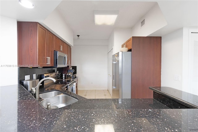 kitchen featuring light tile patterned flooring, dark stone countertops, sink, and appliances with stainless steel finishes