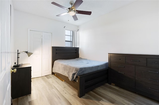 bedroom with ceiling fan, light wood-type flooring, a textured ceiling, and a closet