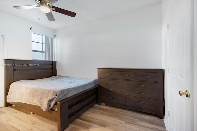 bedroom with ceiling fan, light hardwood / wood-style floors, and a textured ceiling