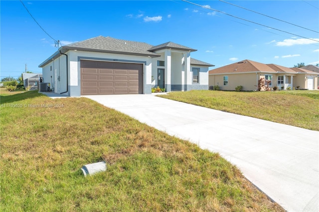 view of front of home with central AC unit, a garage, and a front yard