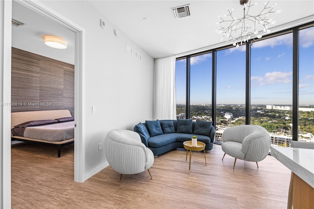 living room featuring light wood-type flooring, a wall of windows, and a notable chandelier