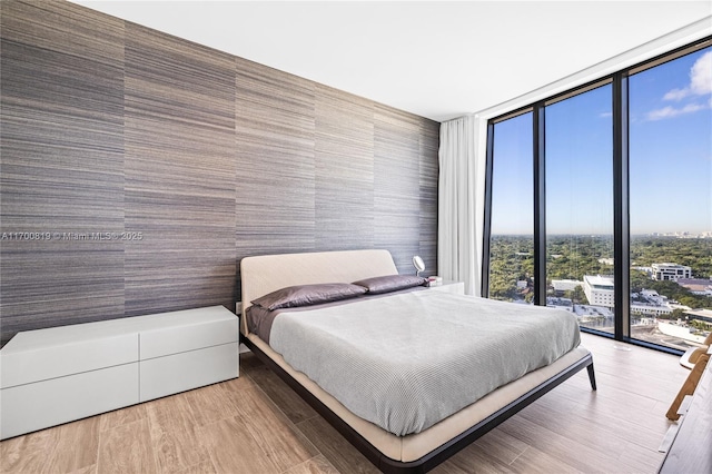 bedroom featuring light wood-type flooring and floor to ceiling windows