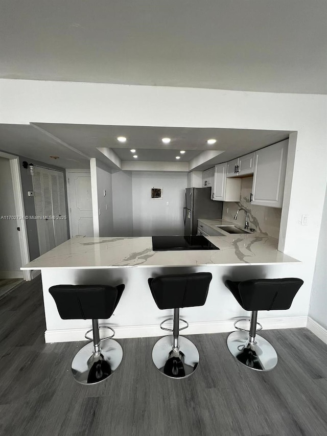 kitchen featuring kitchen peninsula, stainless steel fridge, a breakfast bar area, and sink