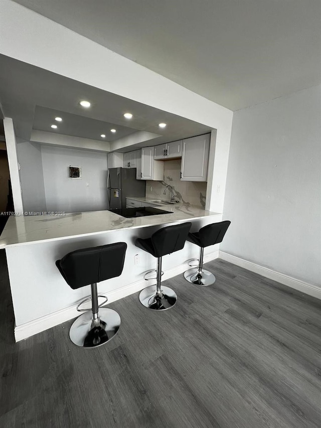 kitchen with white cabinets, a kitchen breakfast bar, stainless steel fridge, and kitchen peninsula