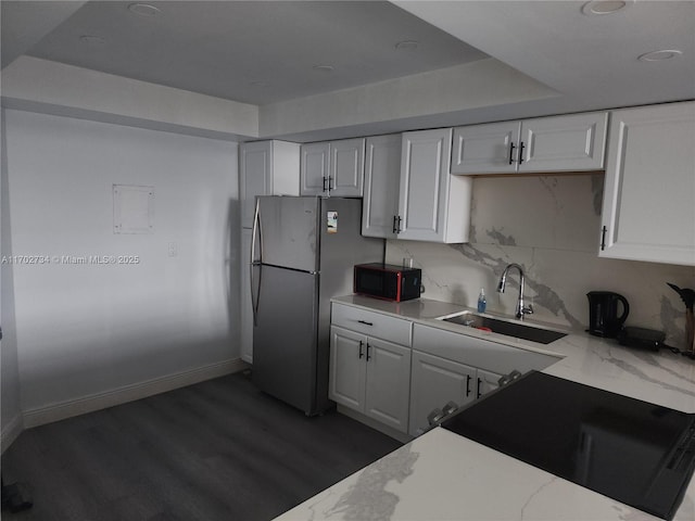 kitchen featuring dark hardwood / wood-style flooring, stainless steel fridge, sink, and white cabinets