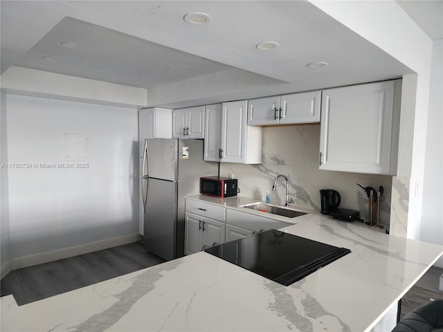 kitchen with white cabinetry, sink, light stone counters, decorative backsplash, and black appliances