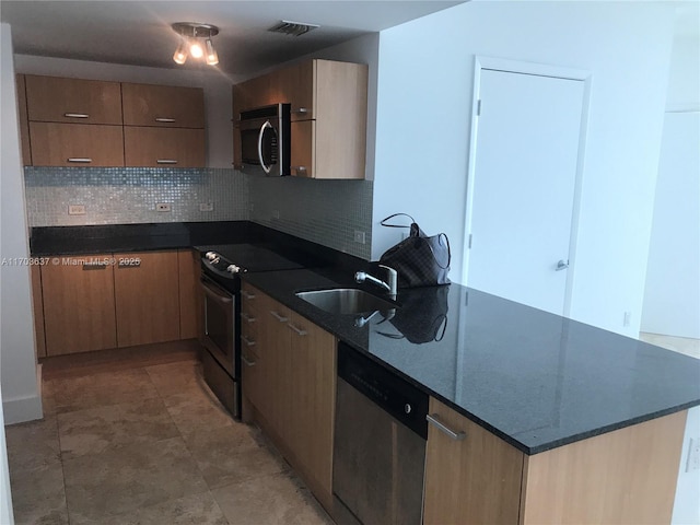 kitchen featuring tasteful backsplash, sink, dark stone countertops, and appliances with stainless steel finishes