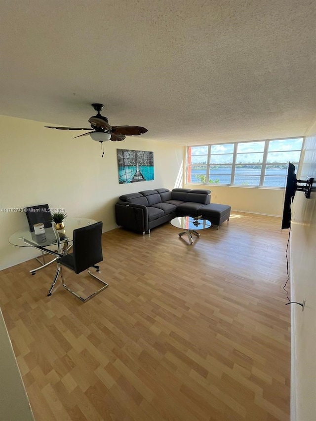 living room featuring ceiling fan, a textured ceiling, and light hardwood / wood-style flooring