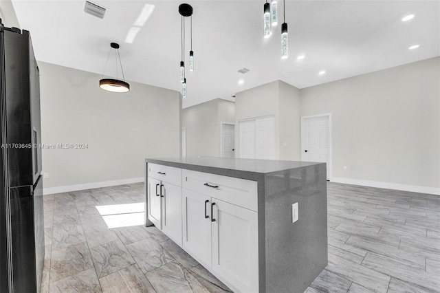 kitchen with pendant lighting, white cabinetry, fridge, and a kitchen island