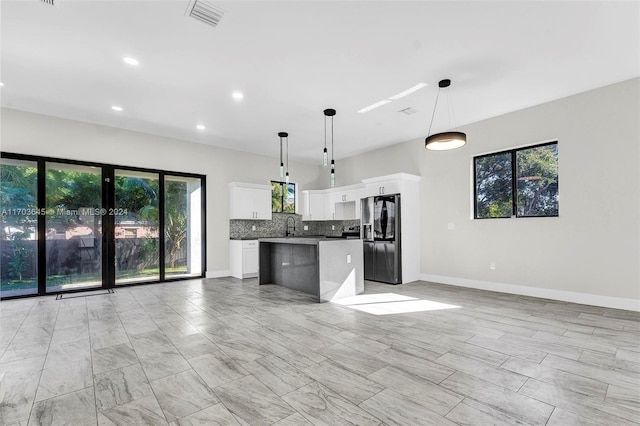 kitchen featuring tasteful backsplash, a kitchen island, fridge with ice dispenser, white cabinetry, and hanging light fixtures