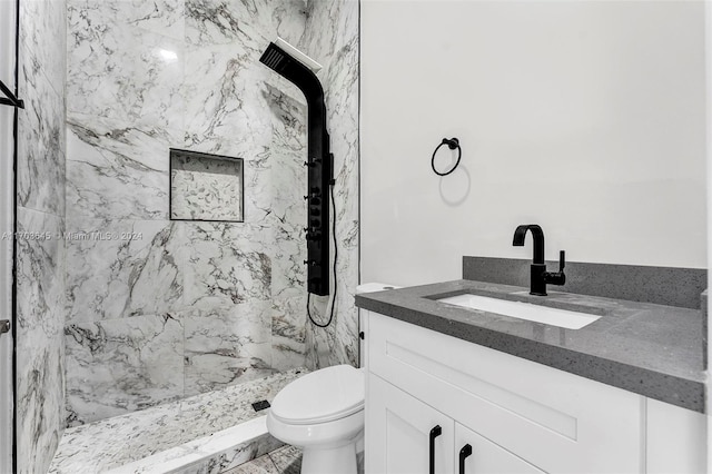 bathroom featuring tiled shower, vanity, and toilet