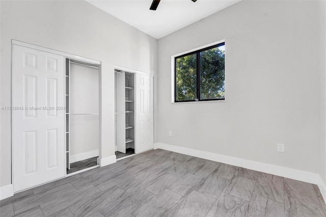 unfurnished bedroom featuring ceiling fan and multiple closets