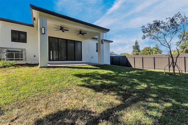 back of property with ceiling fan, a yard, and a patio