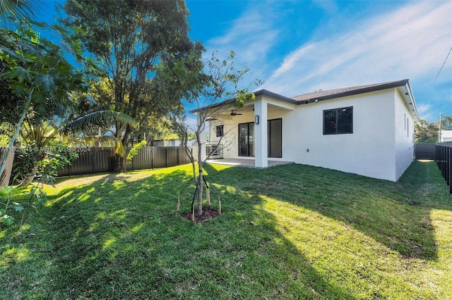 rear view of property with a lawn, a patio area, and ceiling fan