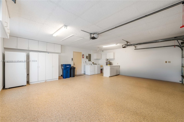 garage featuring electric panel, white fridge, a garage door opener, and independent washer and dryer