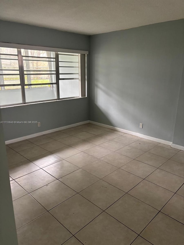 empty room with a textured ceiling and light tile patterned floors