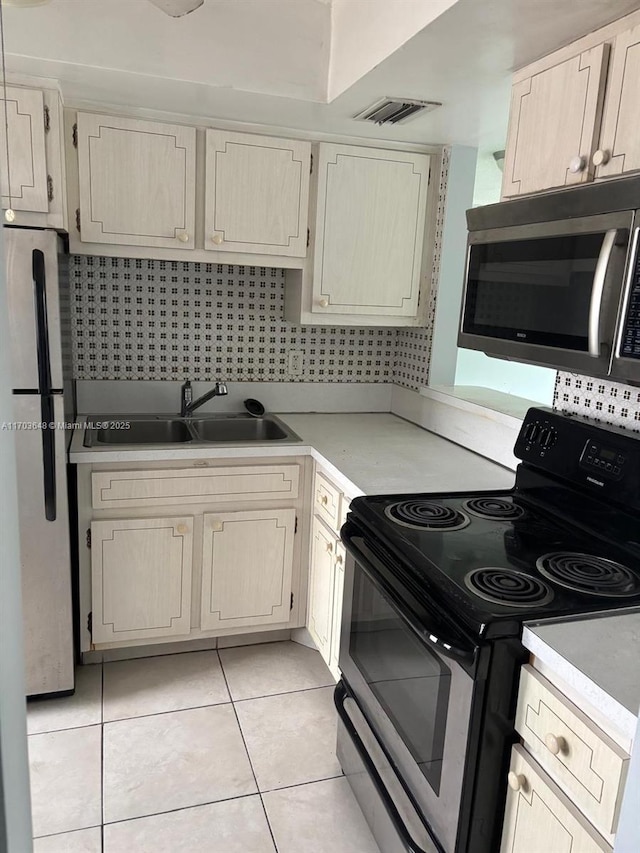 kitchen with tasteful backsplash, appliances with stainless steel finishes, sink, and light tile patterned floors