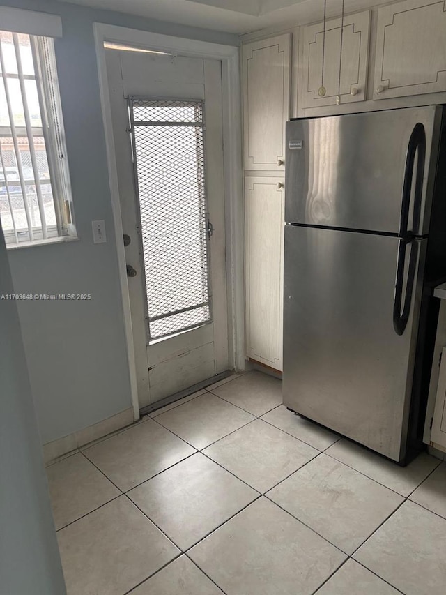 kitchen featuring stainless steel fridge, white cabinets, and light tile patterned flooring