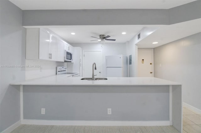 kitchen with kitchen peninsula, white appliances, white cabinets, and sink