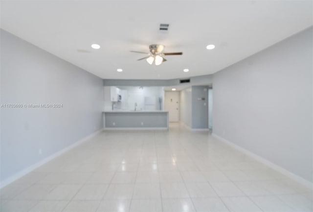 unfurnished living room with ceiling fan, sink, and light tile patterned floors