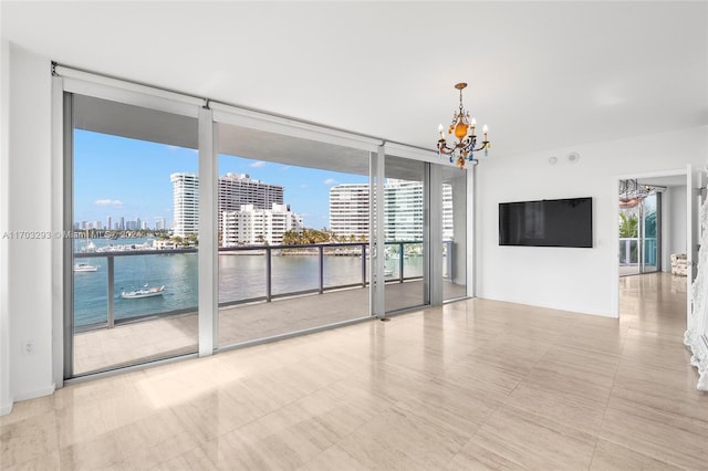 empty room featuring floor to ceiling windows, a water view, and a notable chandelier