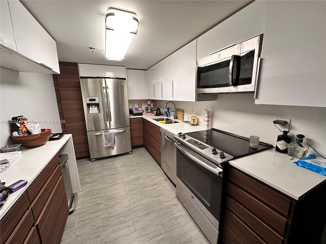 kitchen featuring white cabinets, dark brown cabinets, sink, and appliances with stainless steel finishes