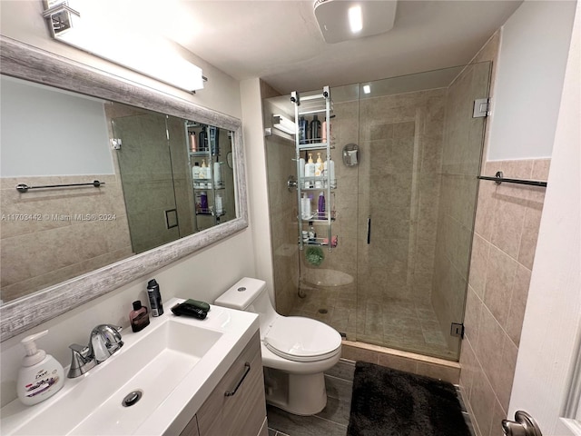 bathroom featuring toilet, vanity, tile walls, and walk in shower