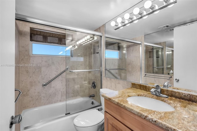 full bathroom with shower / bath combination with glass door, vanity, and toilet