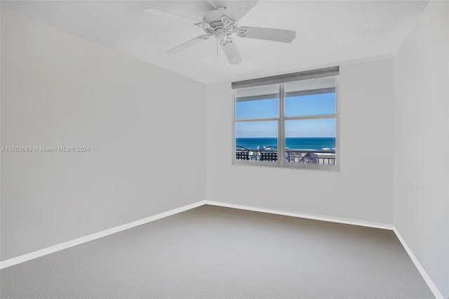 unfurnished room featuring carpet floors, ceiling fan, and a water view