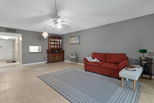 living room with ceiling fan, light tile patterned flooring, and a textured ceiling