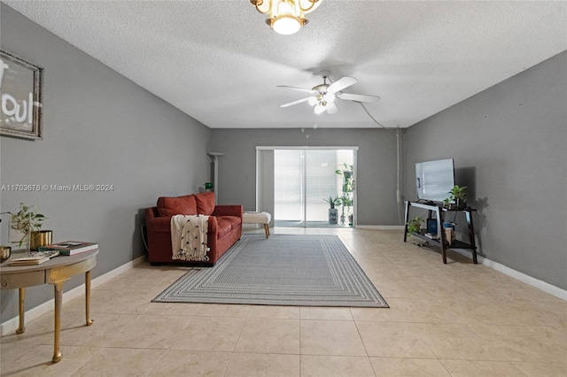 living room featuring ceiling fan, light tile patterned floors, and a textured ceiling