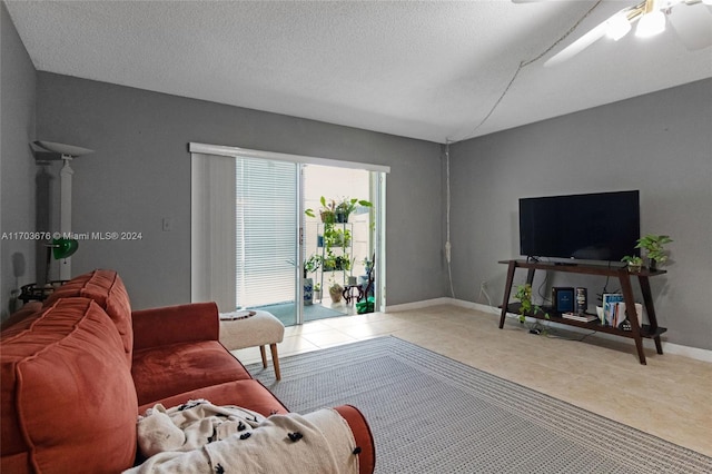 living room with ceiling fan, light tile patterned flooring, and a textured ceiling