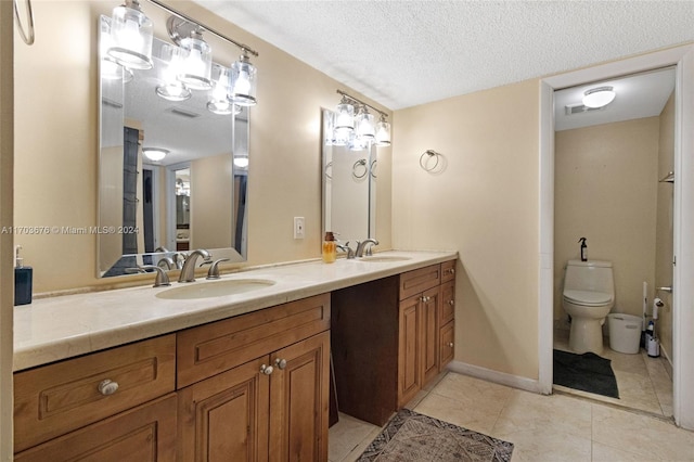 bathroom featuring tile patterned flooring, vanity, a textured ceiling, and toilet