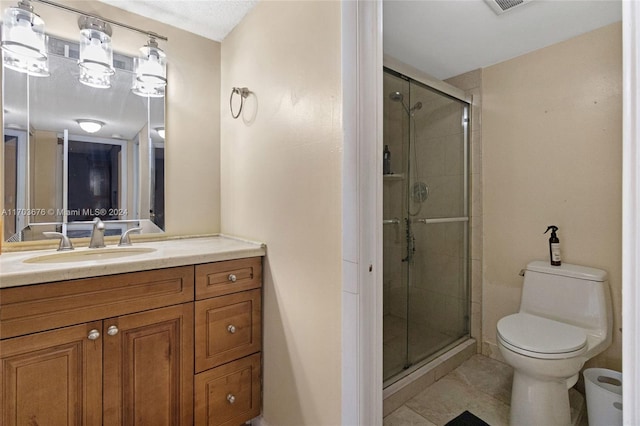 bathroom with tile patterned floors, vanity, a shower with shower door, and toilet