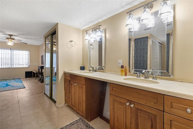 bathroom with ceiling fan, tile patterned flooring, vanity, and a textured ceiling