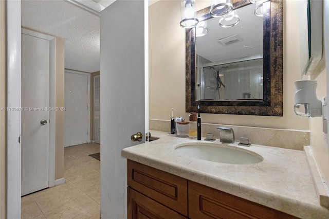 bathroom with tile patterned floors, vanity, a textured ceiling, and walk in shower