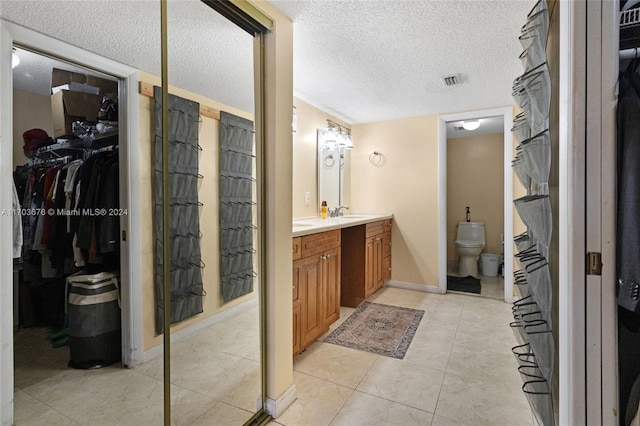 bathroom featuring vanity, tile patterned floors, a textured ceiling, and toilet