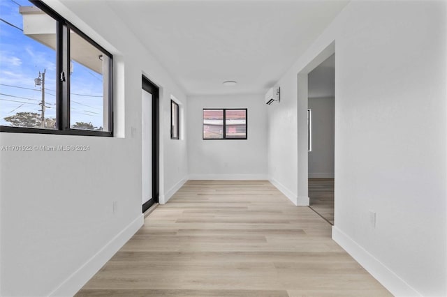 hallway featuring an AC wall unit and light hardwood / wood-style floors