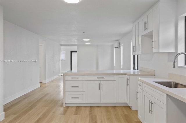 kitchen featuring kitchen peninsula, sink, white cabinets, and light hardwood / wood-style flooring