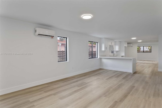 unfurnished room with a wealth of natural light, a wall mounted air conditioner, and light wood-type flooring