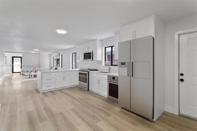 kitchen featuring kitchen peninsula, sink, white cabinets, and stainless steel appliances