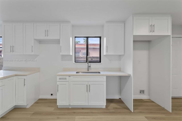 kitchen featuring white cabinets, light wood-type flooring, and sink