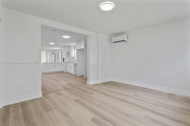 unfurnished living room featuring a wall mounted air conditioner and light hardwood / wood-style floors